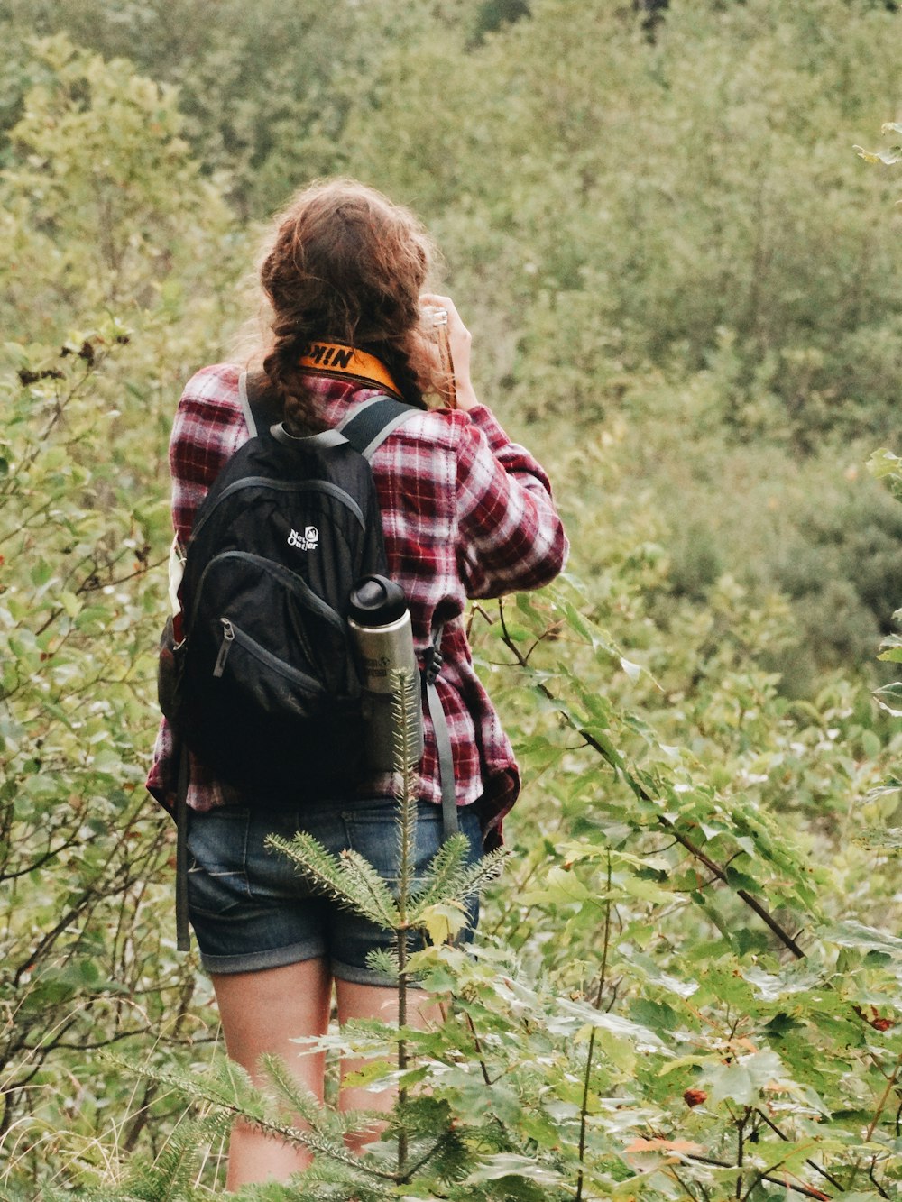 woman wearing red and white blouse carrying backpack