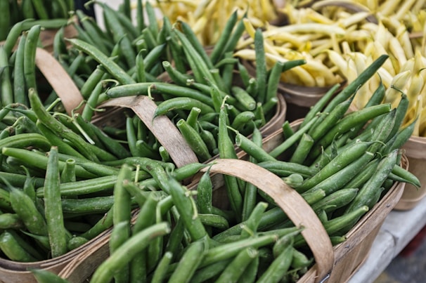 Fresh green beans neatly arranged in a rustic wooden basket.