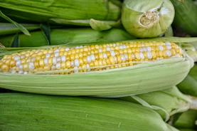 Bright frozen sweet corn kernels spilling from a bag onto a clean white surface