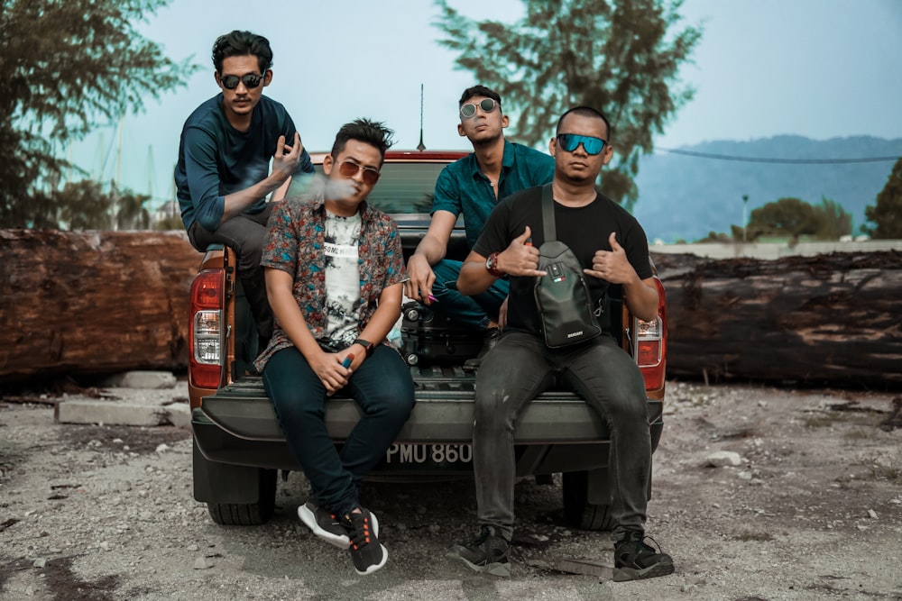 four men wearing sunglasses sitting on pickup truck