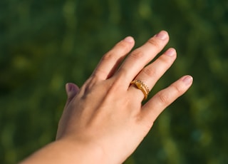person's hand wearing gold-colored ring