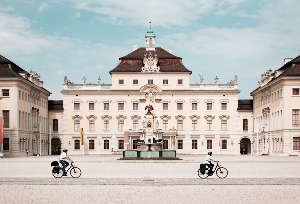 person riding bike in front of white building during daytime