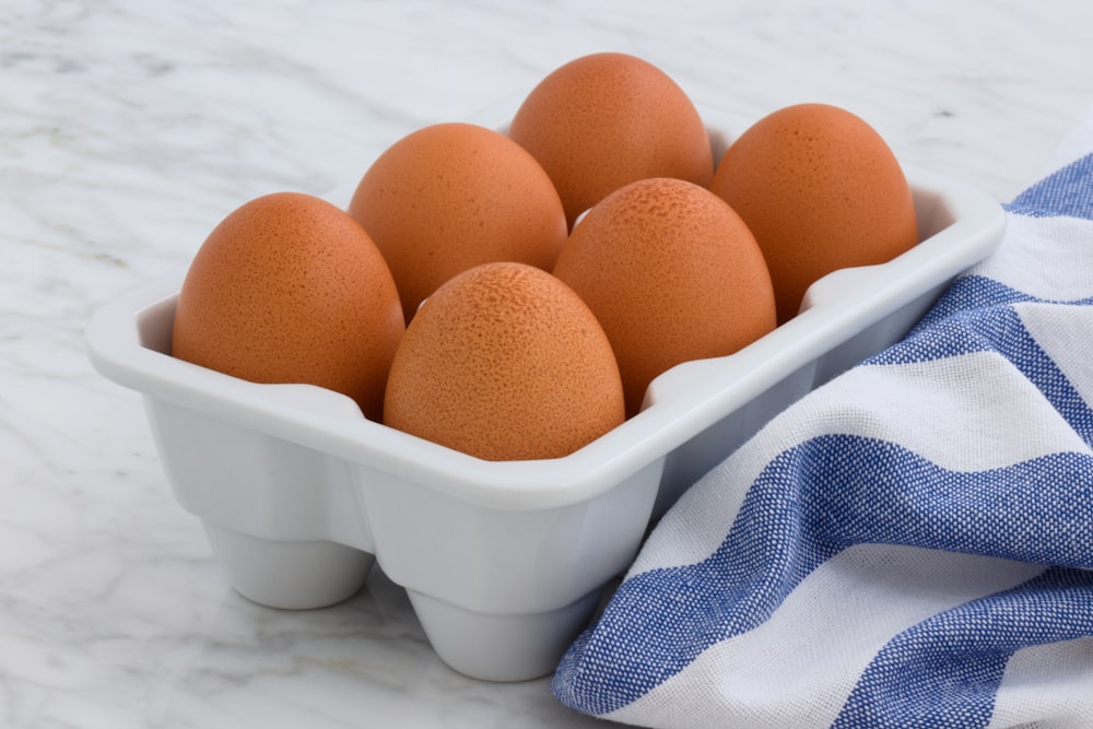 six œufs bruns dans un plateau blanc