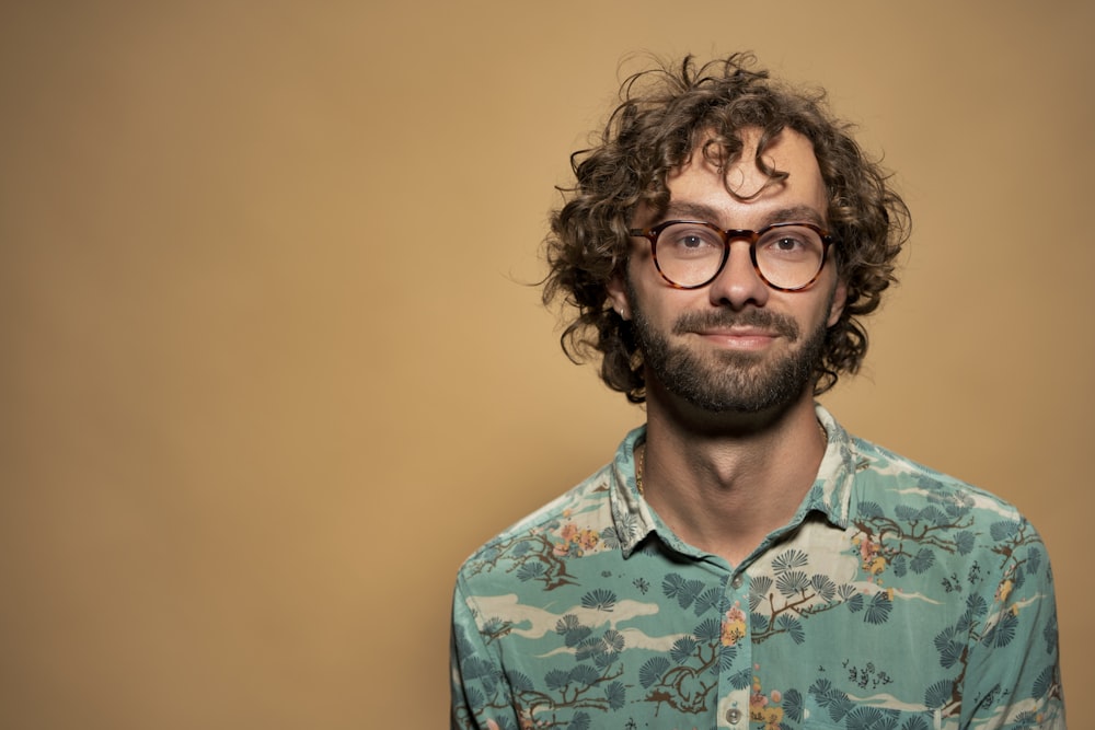 a man with curly hair and glasses looking at the camera