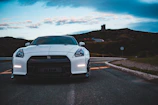 Sporty coupe gleaming under a cloudy sky on a winding road.