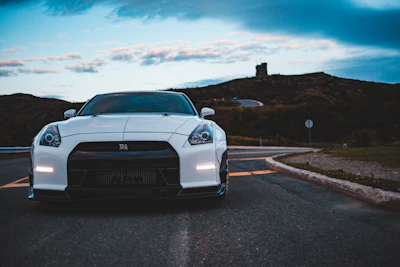 Sporty coupe gleaming under a cloudy sky on a winding road.