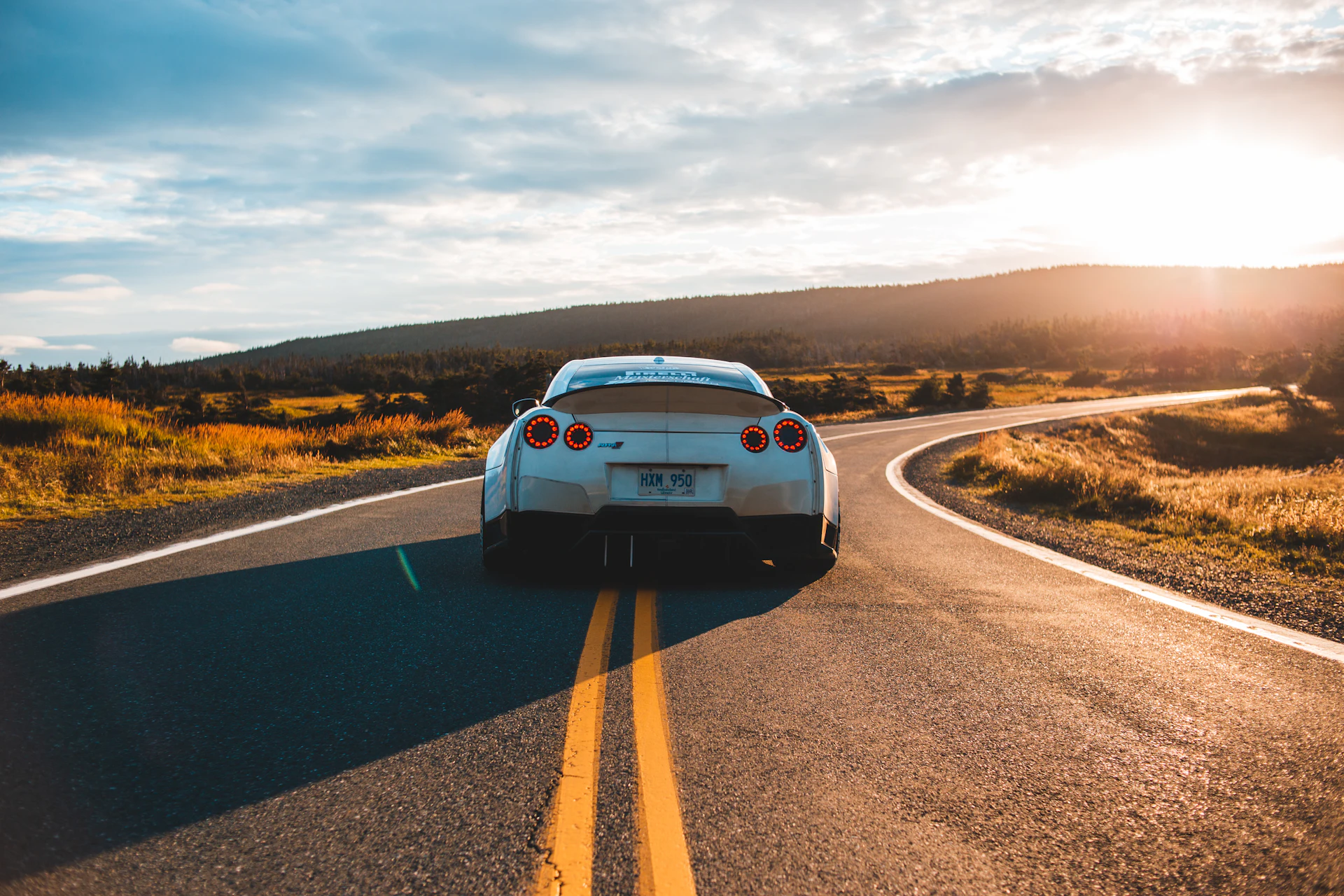 Voiture sur une route de campagne au coucher du soleil