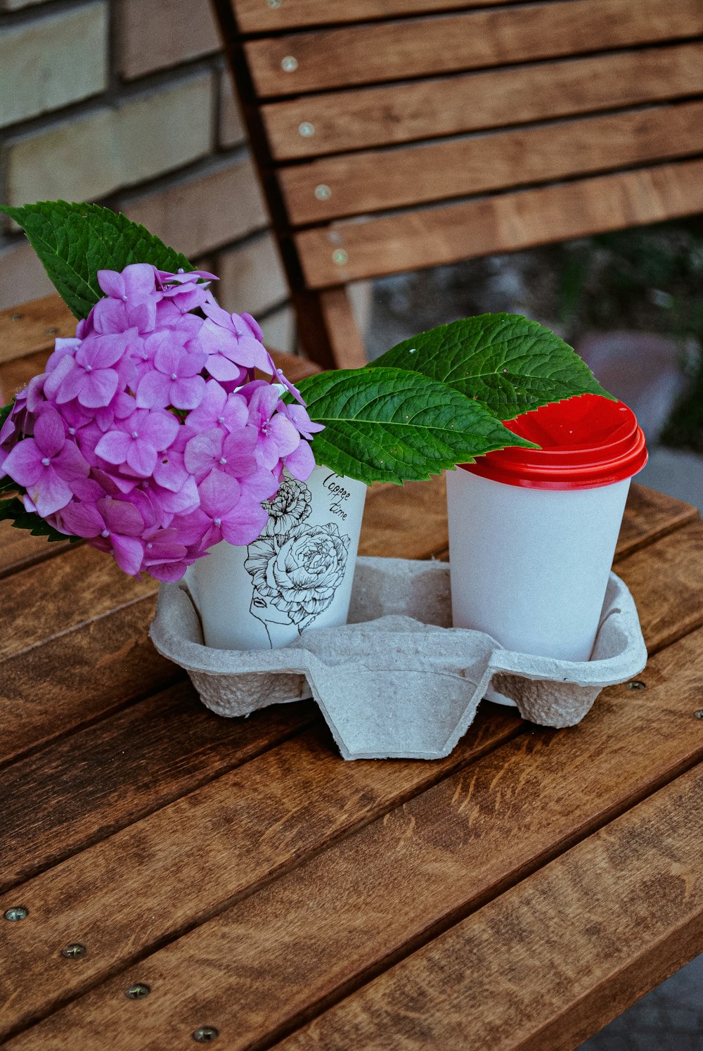 a cup of coffee and a flower on a wooden table