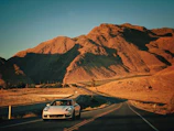 Porsche Macan cruising along a desert highway with red rocks in the background.