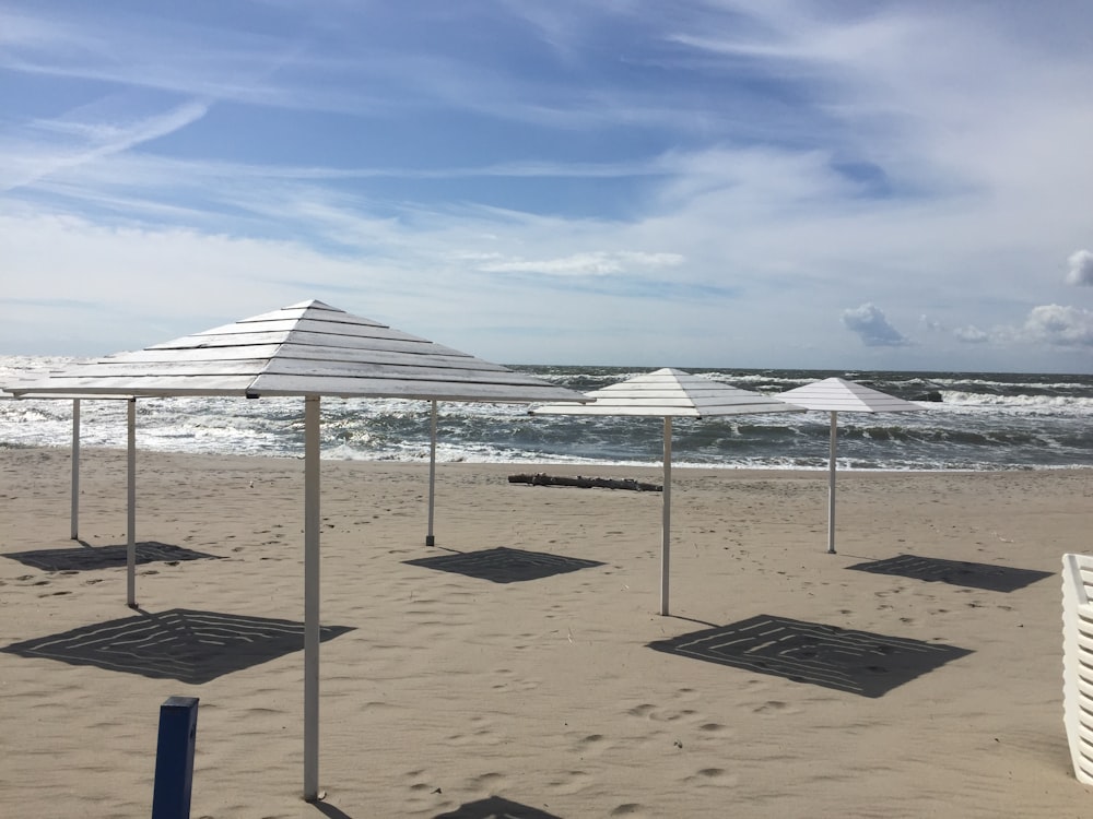 a row of white umbrellas sitting on top of a sandy beach