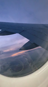 An elegant airplane window view showing a calm sky at sunset.