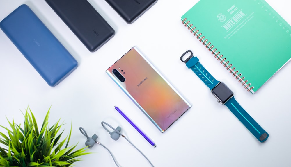 smartwatch beside book and smartphone on white surface