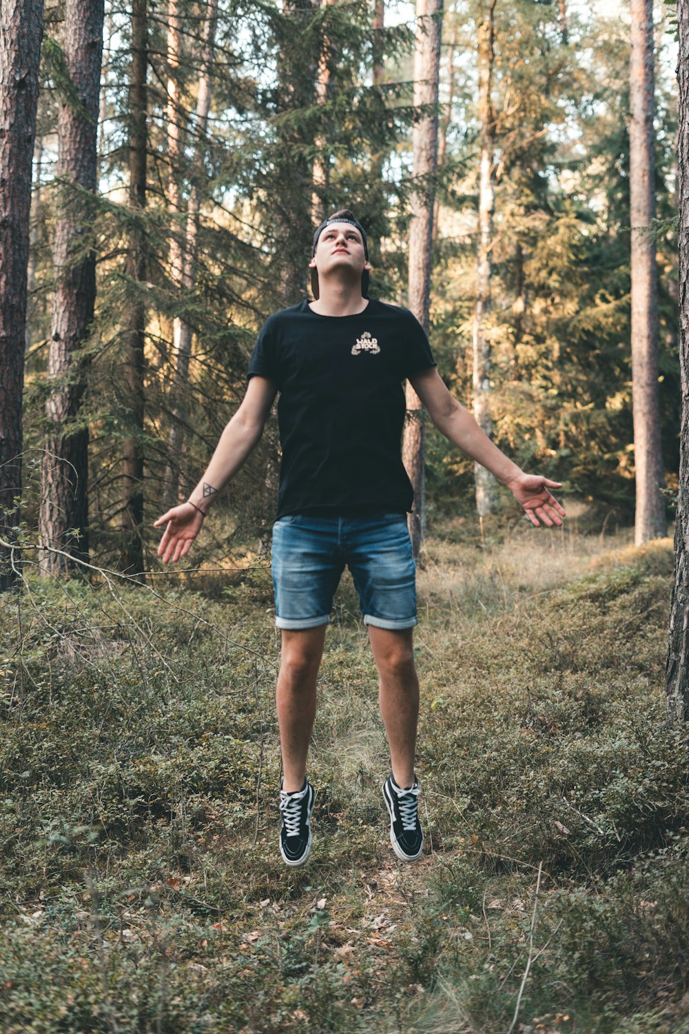 man jumping near trees