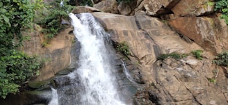 Crystal clear waters of Ouzoud waterfalls cascading down rocky cliffs surrounded by lush greenery.