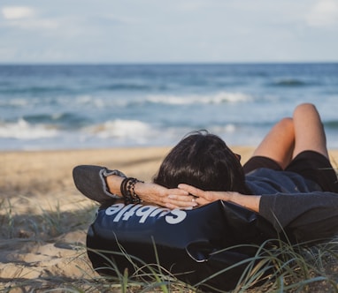 woman lying on grass front of sea at daytime