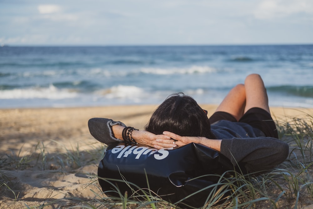 woman lying on grass front of sea at daytime