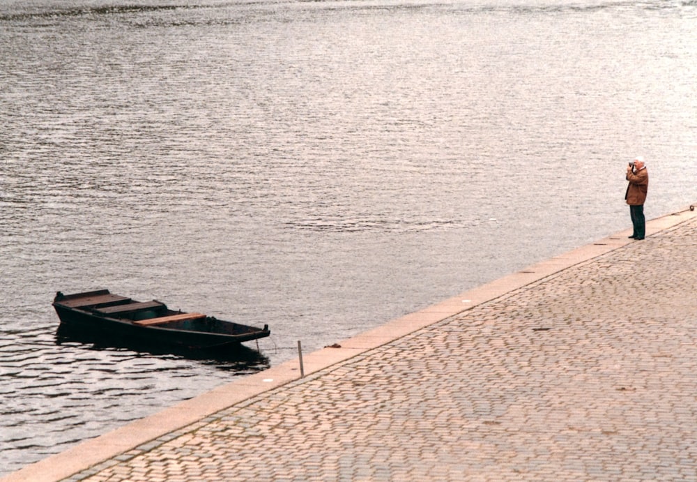 man standing at the bay near boat