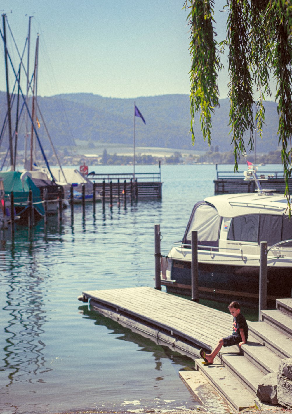 boy standing on dock stairs near boat