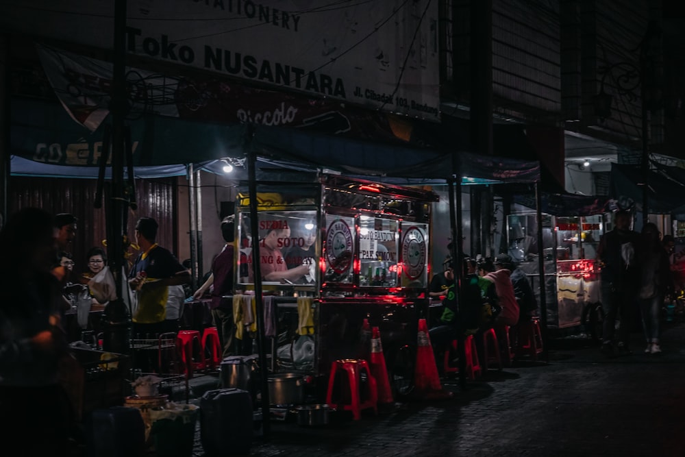 a group of people standing around a booth at night