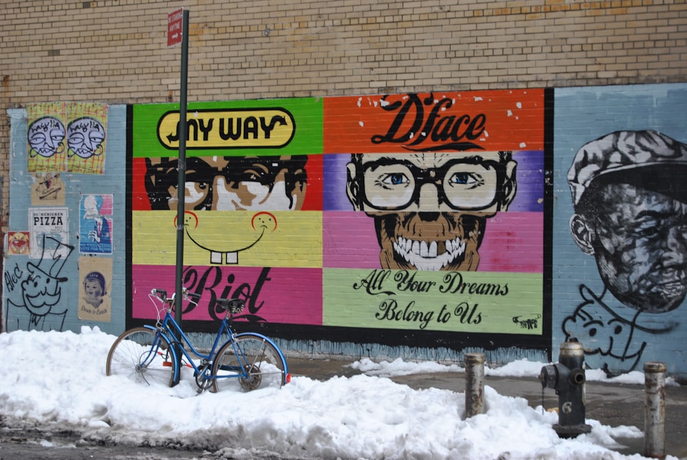 blue bicycle parked beside road covered with snow