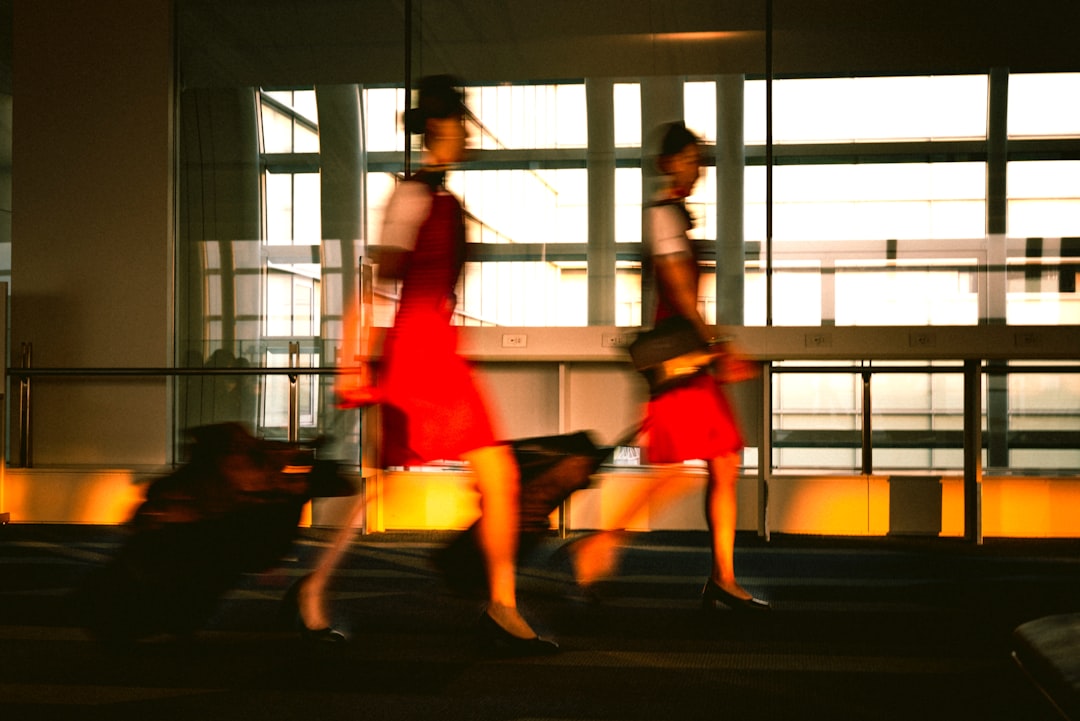 two women walking near building, two stewardess are walking in the airport.