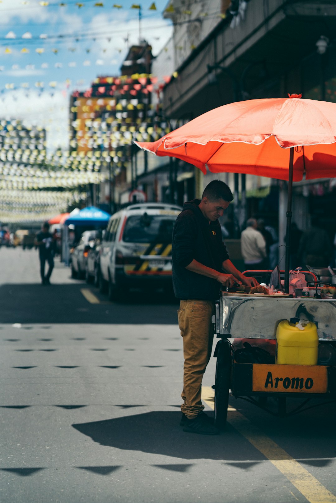 man standing front of food kart at daytime