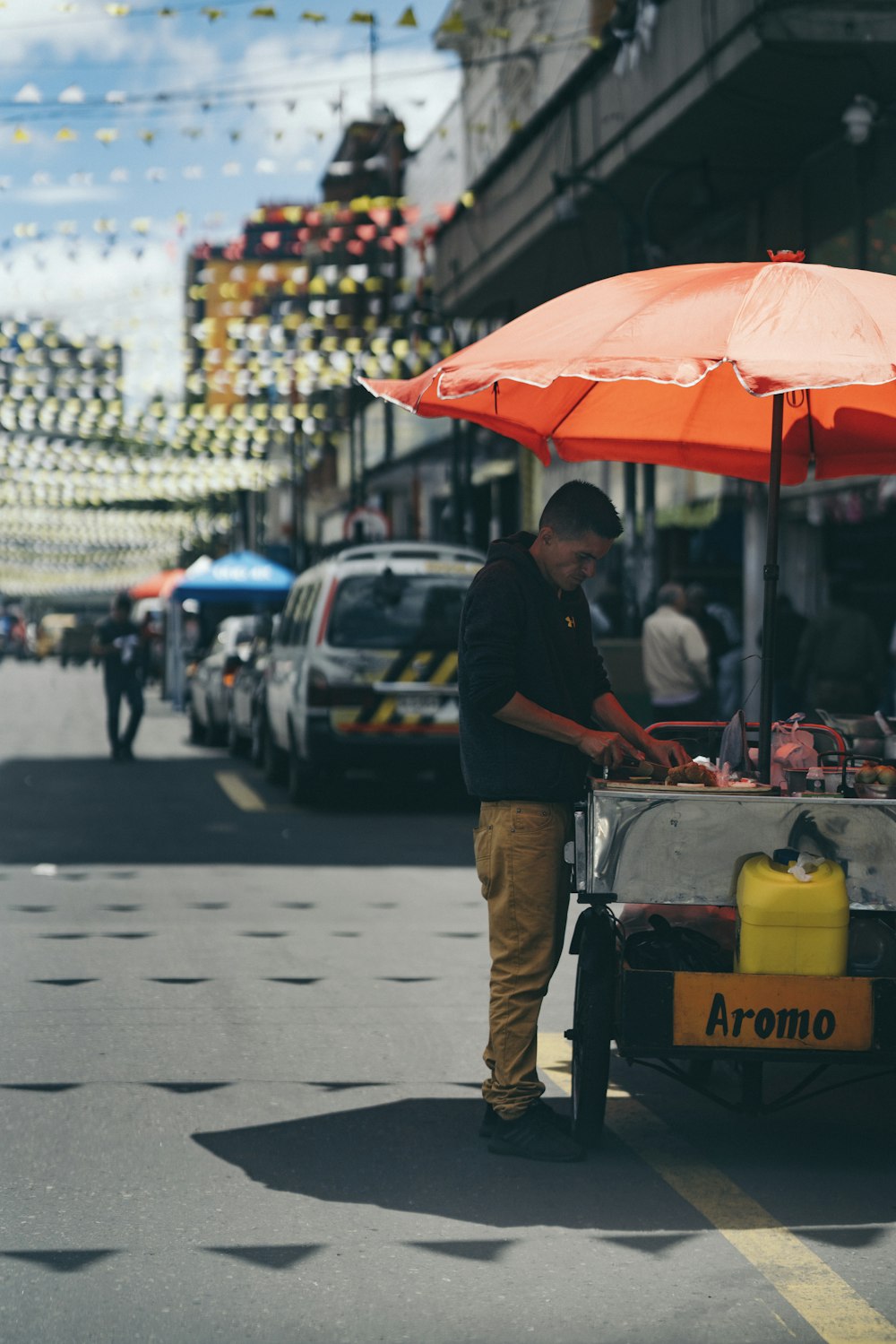 man standing front of food kart at daytime