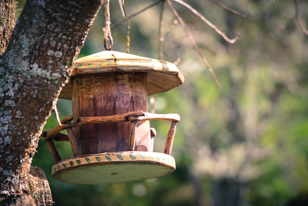 Casita marrón para pájaros colgando de un árbol