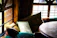 A sunlit window bench adorned with soft linen pillow shams and a rattan cube unit nearby.