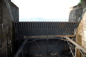 Hands holding a piece of scrap metal with shipyard in background.