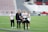 A group of women wearing Washington Spirit apparel are on a soccer field, likely preparing for a game or practice. One woman holds a water bottle and they appear to be in a casual and relaxed mood. There are empty seats in the background, suggesting the setting is a stadium.
