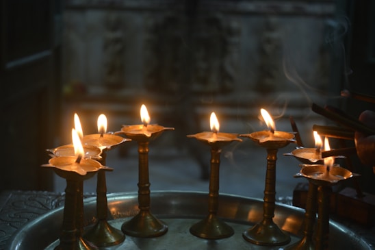 A serene arrangement of dhoop sticks and cones beside a brass diya, softly lit to evoke a calm, spiritual atmosphere.