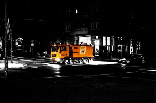 A rugged street sweeper machine cleaning a city road on a bright day