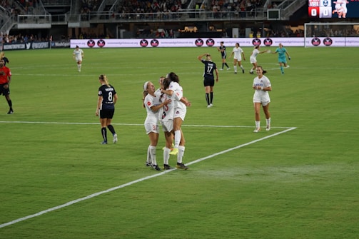 Young soccer players celebrating a goal with a sponsor's banner in the background