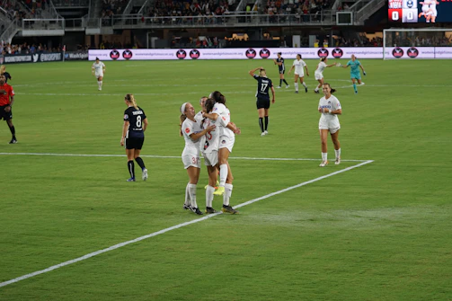 Young female football players celebrating a goal on a sunny field in Esposende.