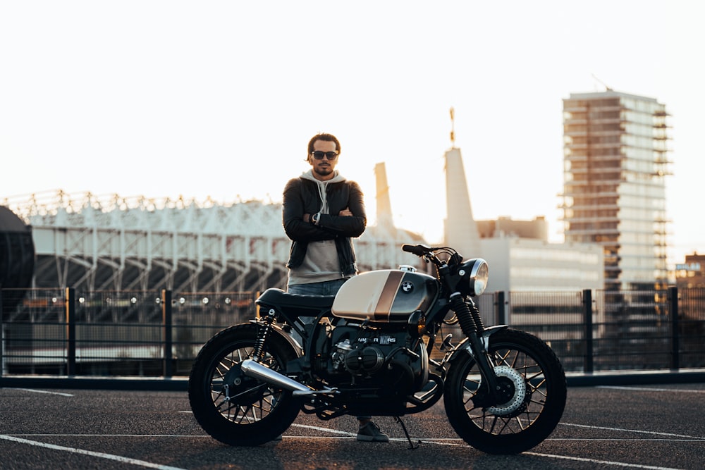 motorcycle parked in front of standing man crossing his arms