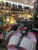 A bustling store with numerous colorful socks and slippers displayed on racks. The foreground features a pair of pink slippers with the inscription 'SMILE' on them, while the background shows rows of hanging socks in various colors and patterns.