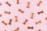 Various dog biscuits in the shape of bones are scattered across a light pink background. The treats are in different shades of brown.