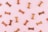 Various dog biscuits in the shape of bones are scattered across a light pink background. The treats are in different shades of brown.