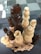 Wooden chess pieces are stacked in a tower formation, with both light and dark pieces arranged in an intricate manner. The chessboard in the background has a checkerboard pattern with alternating light and dark squares.