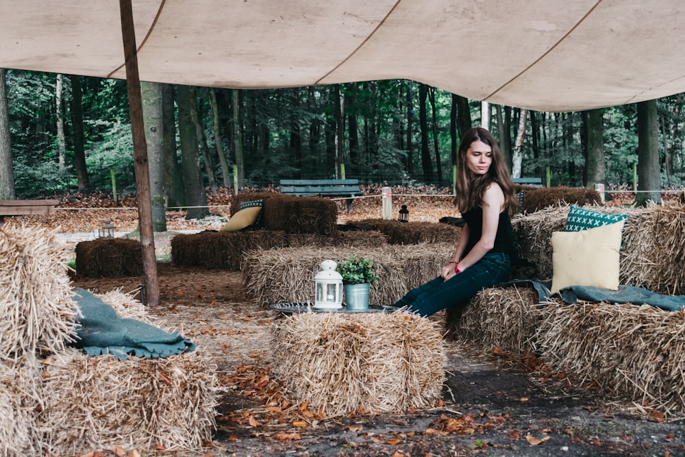 woman sitting on rolled hay at daytime