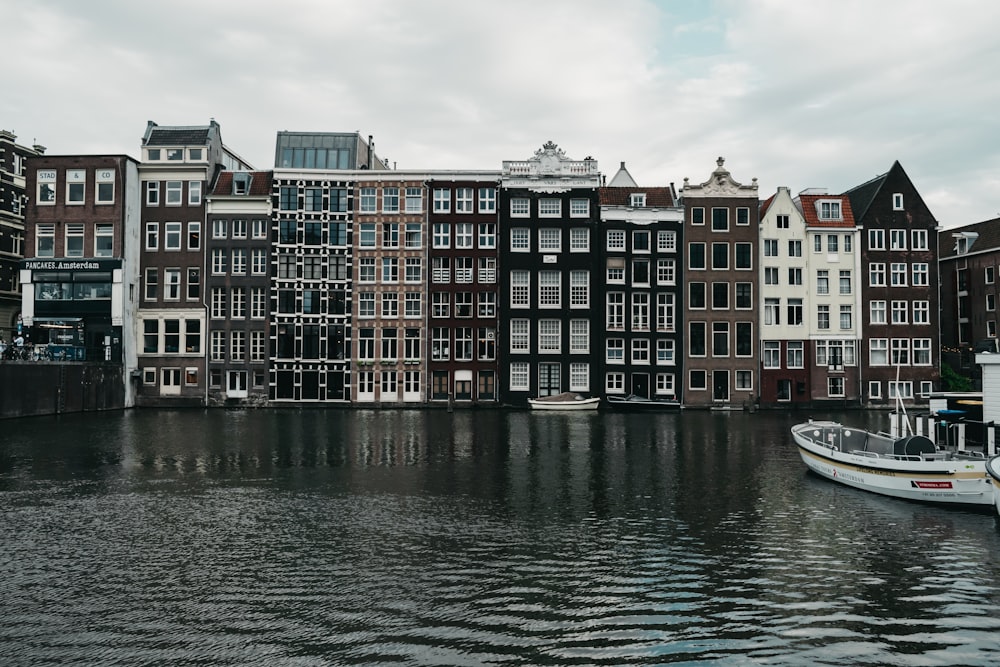 grayscale photography of buildings beside body of water