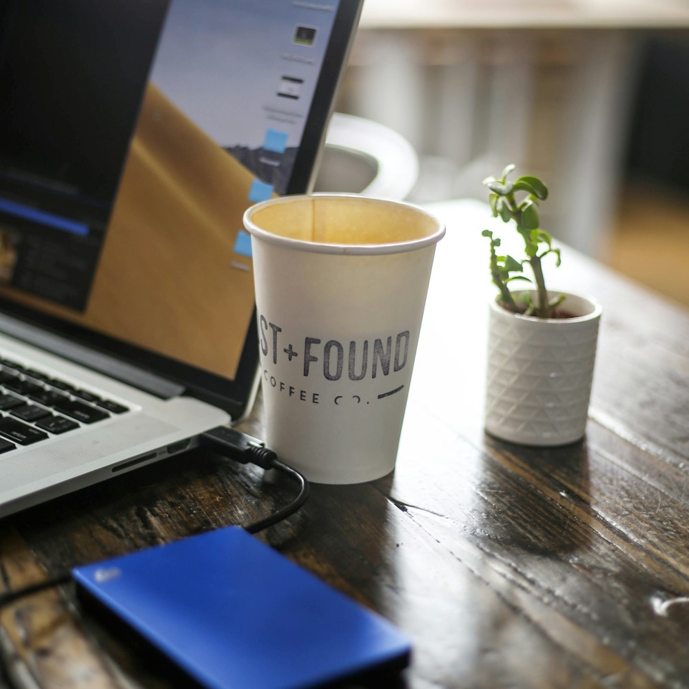 white disposable cup on brown wooden table