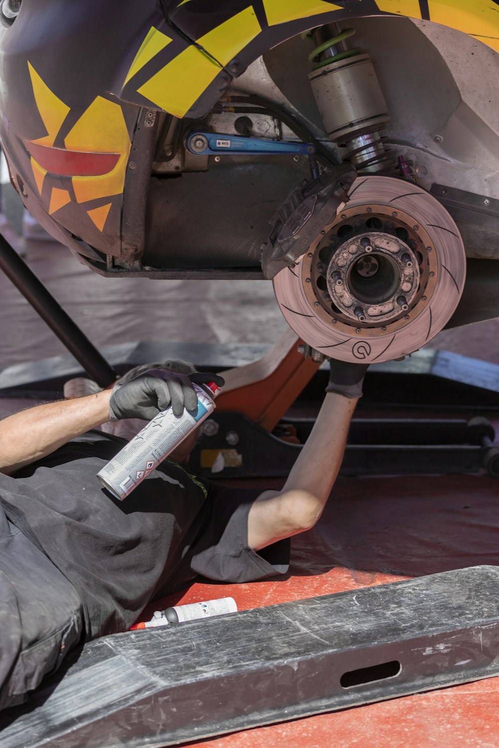 man fixing vehicle while holding spray can