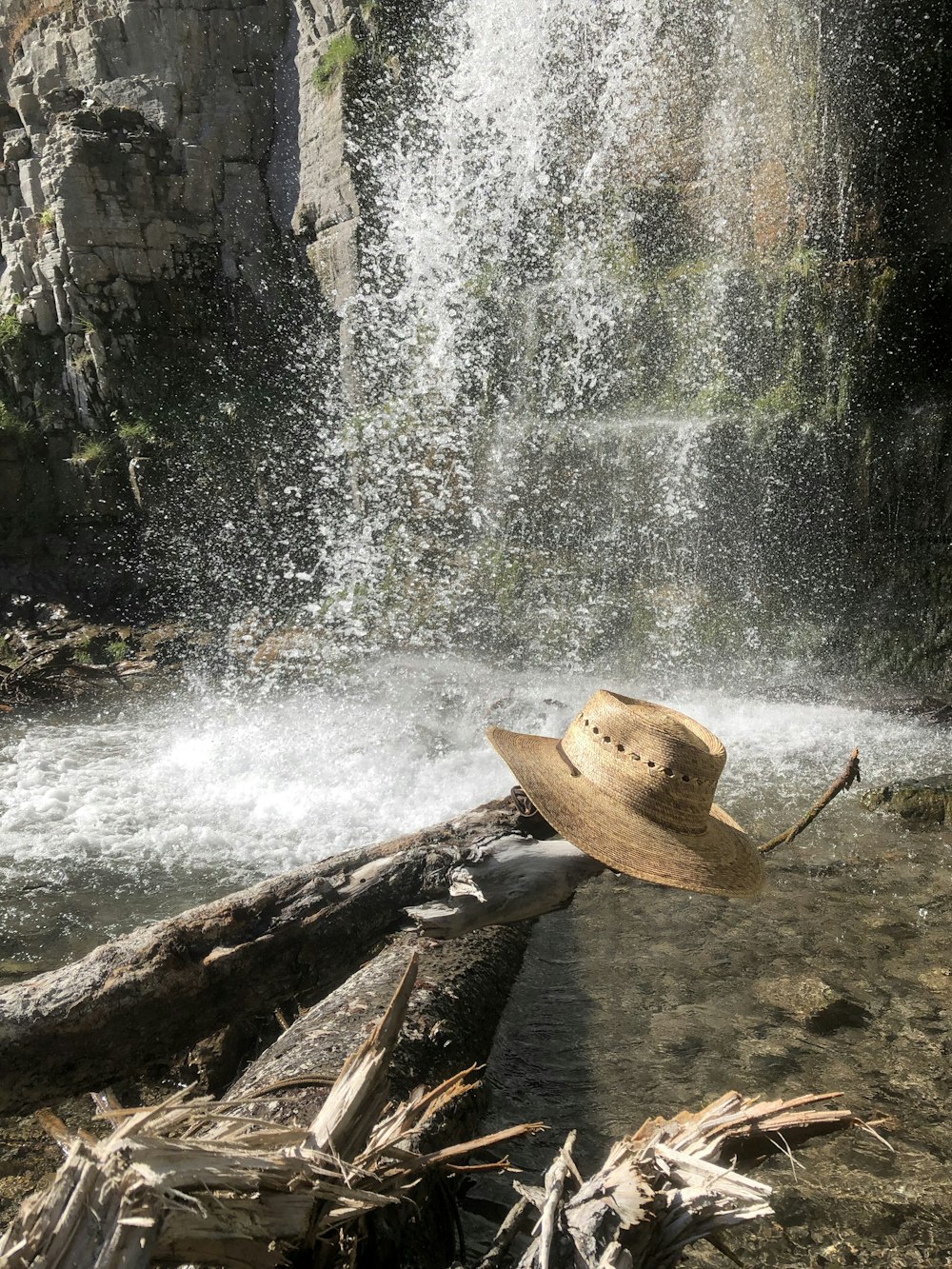 brown sun hat on edge of log near waterfalls
