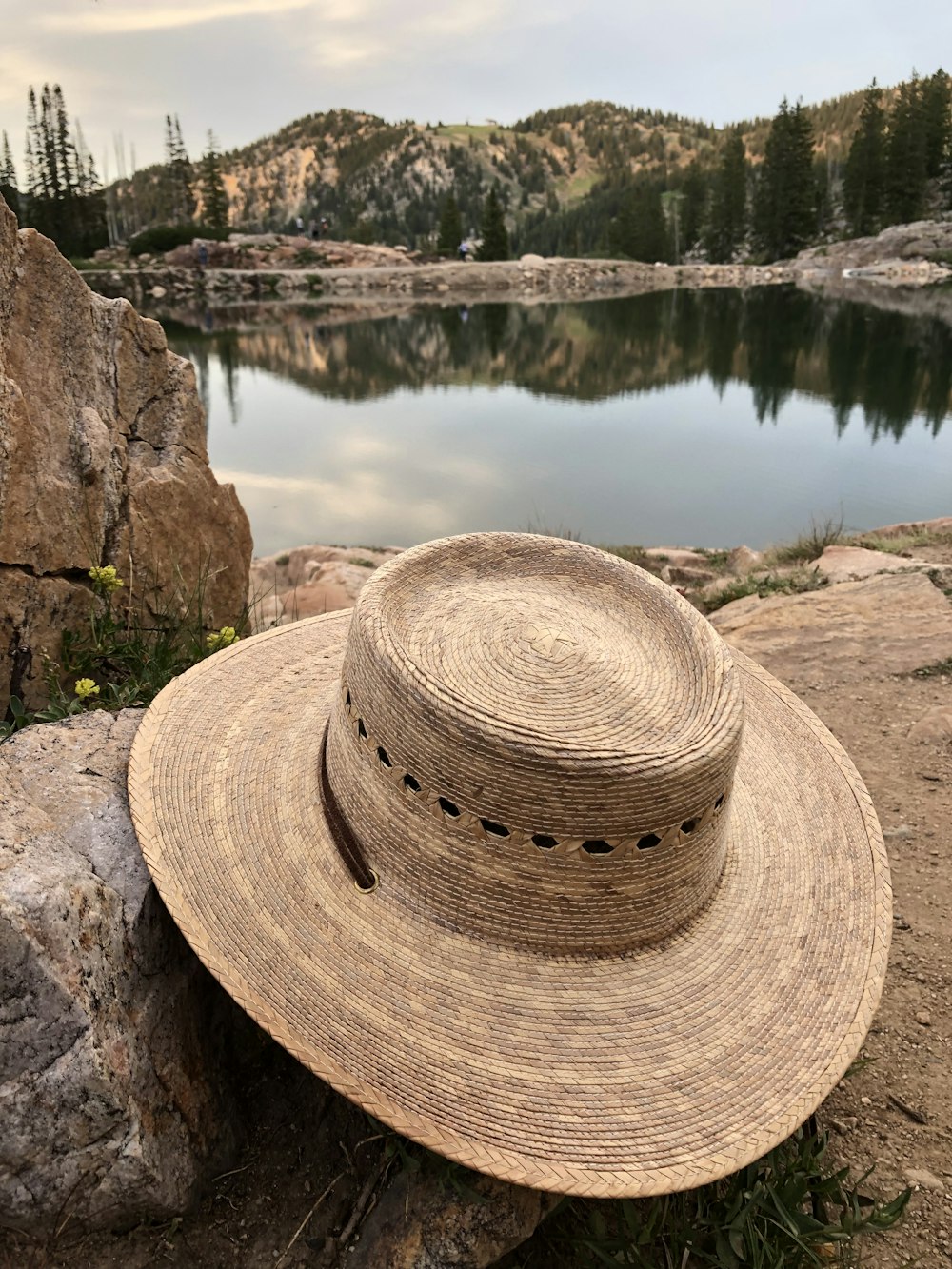 a hat sitting on top of a rock near a lake