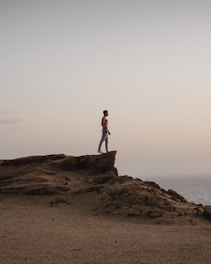 topless man standing on rocky hill