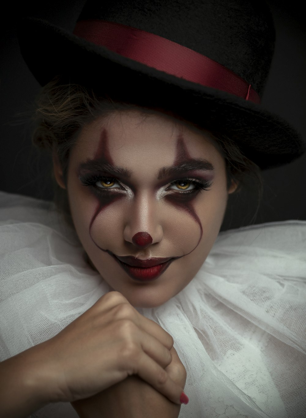 a woman wearing a clown makeup and a top hat
