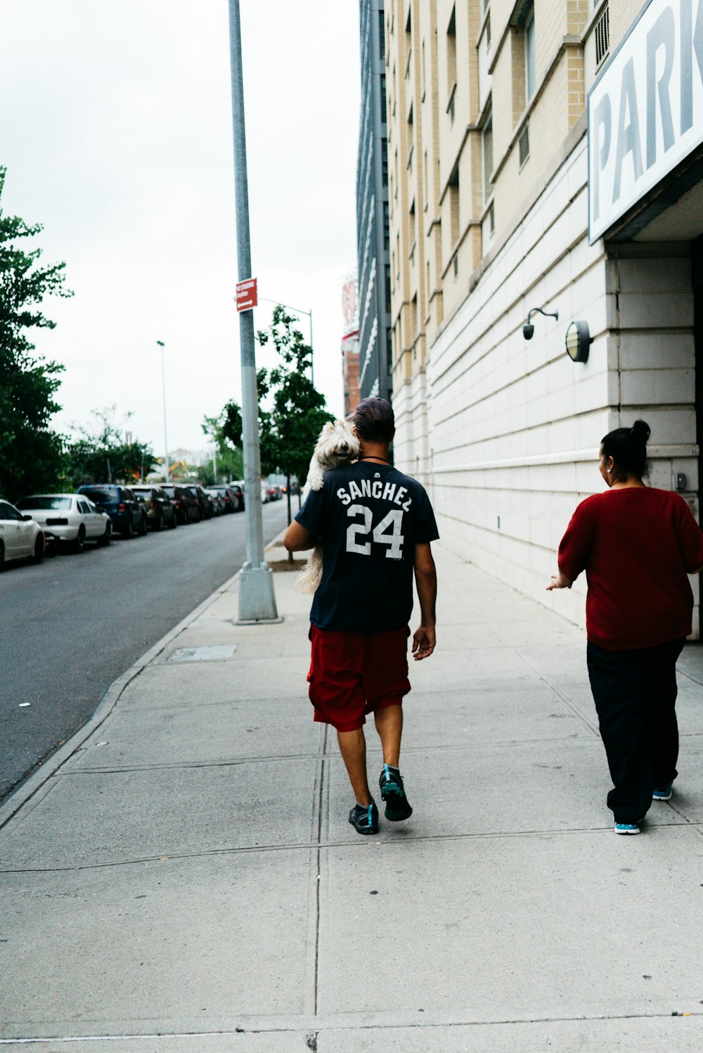 person in black jersey shirt walking on sidewalk during daytime