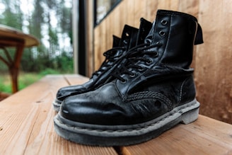 Short boots displayed on a rustic table with greenery in the background.